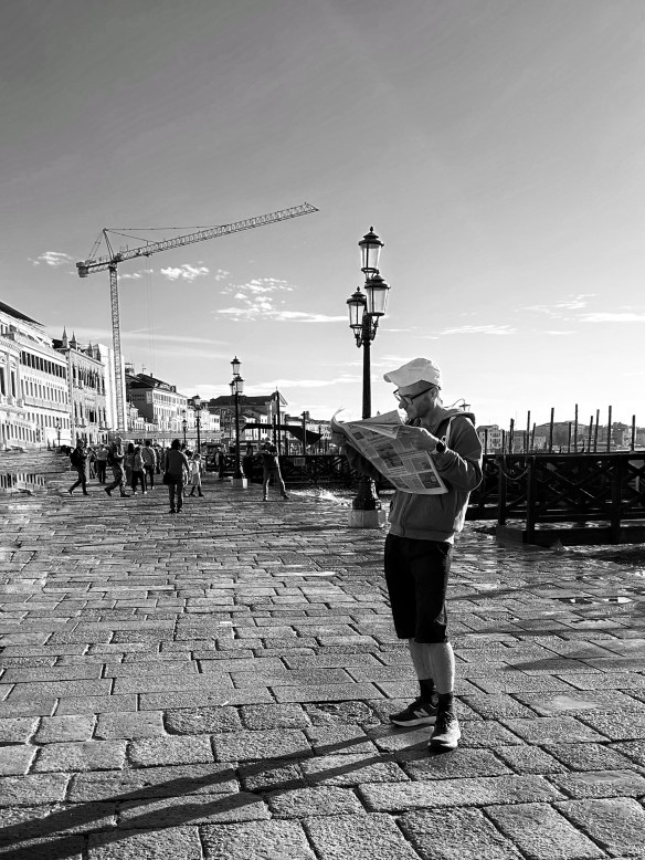 un turista che legge, assorto, un quotidiano